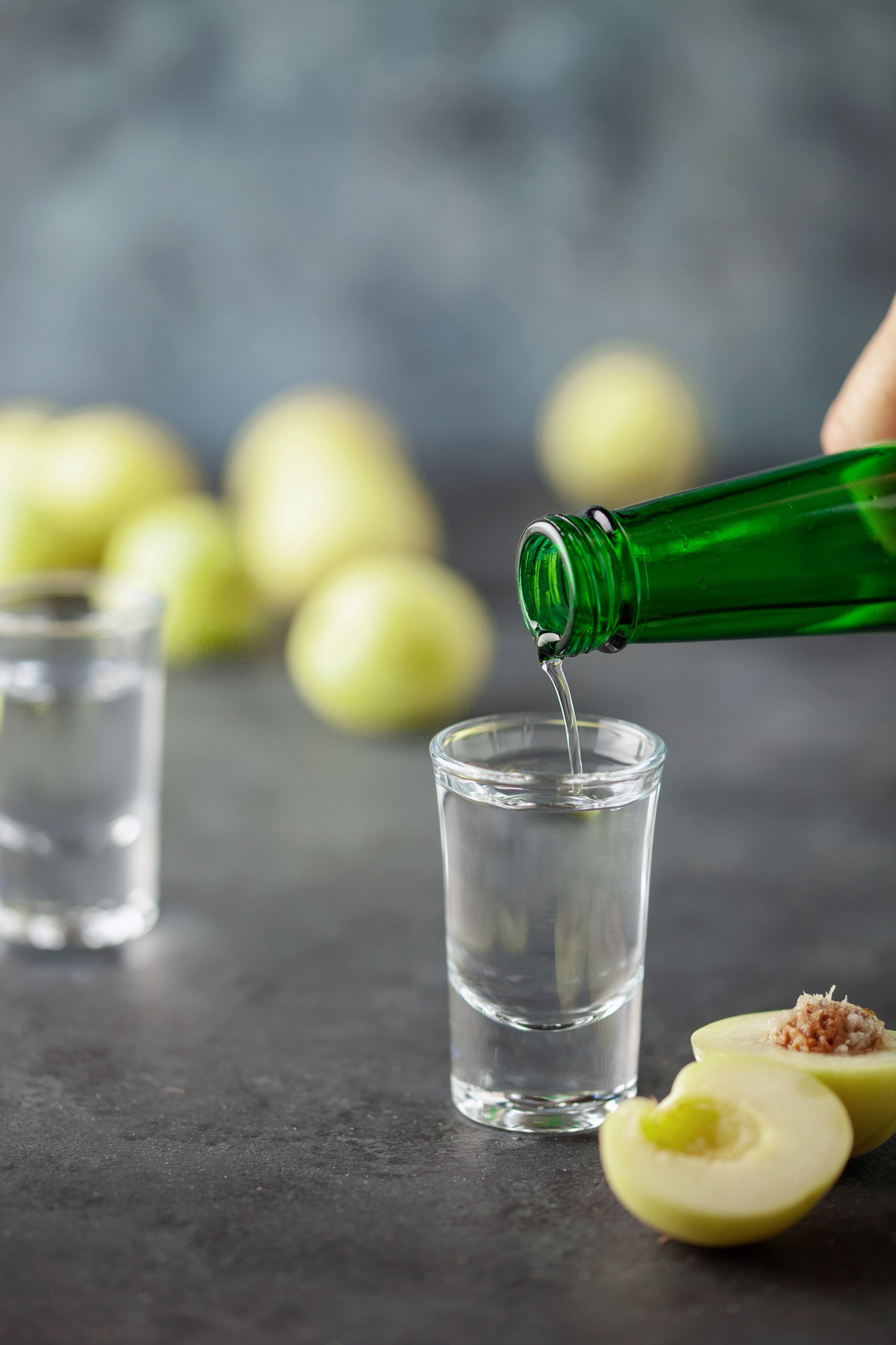 Plum soju or plum vodka, strong drink in shot glasses on the table. Corean national alcoholic drink